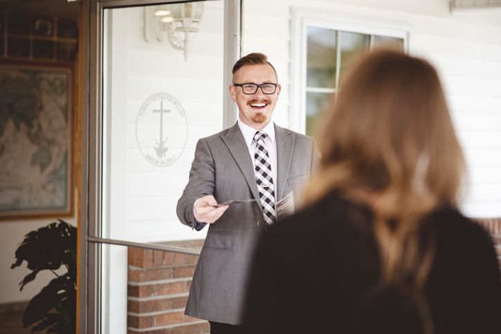 A pastor warmly greeting a church member at the door